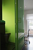 Blick ins offene Bad auf Toilette vor grün gefärbter Glaswand