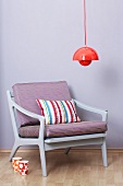 Rote Hängeleuchte über einem Sessel in 50er-60er Jahre Design