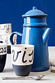 Blaue Teekanne aus Emaille und Tassen mit holländischer Schrift