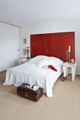 Weisses Schlafzimmer mit rotem Paravent am Bettkopf