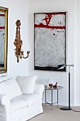 Ecke eines Wohnzimmers mit Sofa, Beistelltisch, Wandkerzenhalter und Gemälde