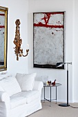 Corner of a living room with sofa, side table, wall candle holder and paintings