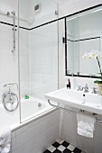 A white bathroom with bathtub and black and white floor tiles