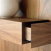 A wood panelled shelf with an open drawer