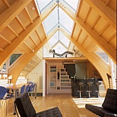 An open-plan living room with a dining area and a mini kitchen in a converted attic with skylights