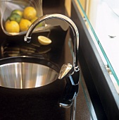 A stainless steel sink in a black granite work surface