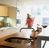 A wooden kitchen work surface with an integrated sink and designer taps