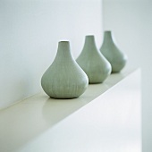 Drei gleiche Vasen auf einer Ablage