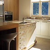 A fitted kitchen with an island counter and a sink under the window