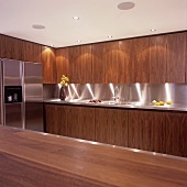 Eine beluchtete Küche mit Holzfronten und Kühlschrank mit Edelstahlfront