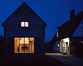 A renovated house by night with illuminated windows and a view of a fireplace