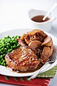 A pork chop with onions, apples and peas