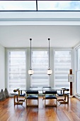 Moderner Wohnraum mit Oberlicht und Hängelampen über Esstisch mit Retro Lederstühlen