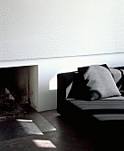 Wall panel with subtle white and pastel grey pattern above open fireplace next to modern black sofa