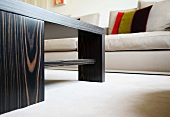 Coffee table in exotic wood and upholstered sofas with scatter cushions on a white rug