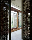 Durchblick zwischen Trennelementen aus Bambusmatten auf grossflächige Schiebetürverglasung