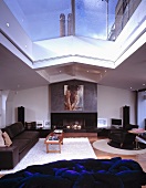 Leather seating in front of chimney breast with large portrait and deep blue furniture with tangled cushions under a skylight showing a view of a blue city sky