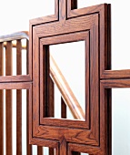 Handwerklich aufwendige Holzrahmung einer Spiegel-Schiebetür mit Abbild eines Treppengeländers