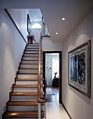 Recessed spotlights on treads of wooden staircase with white and wood-coloured elements in an English house