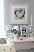 Blumentopf mit weisser Blüte und gerahmte Photographie auf weißem Sekretär im Rokokostil