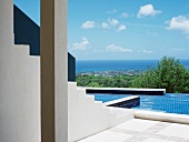 White masonry stairs leading to pool complex with blue tiles and sea view