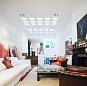 Helles Sofa und Ledersessel am Kamin im offenen Wohnraum mit quadratischen modernen Deckeneinbauleuchten
