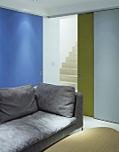 Light grey sofa in front of coloured, part-opened sliding doors with a view of staircase