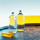 Full bottles and yellow soap on mosaic floor tiles