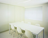 Puristischer Raum mit weißem Tisch und Bauhausstühlen vor Einbauschrank