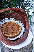 A Linz tart in a basket on a tree stump in the winter
