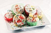 Muffins with icing, colourful sprinkles and sugar ornaments