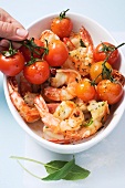 Herb prawns with cherry tomatoes being placed in an oven proof dish