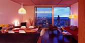 Offener moderner Wohnraum mit Essplatz und raumhohen Terrassenfenstern mit Abendstimmung