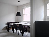 View through wide doorway to modern dining area with bench in front of window