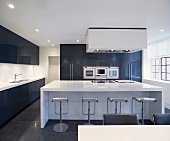 Open-plan designer kitchen with bar stools in front of a white kitchen island