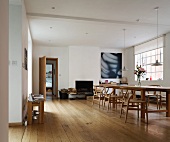 Loft-style living space with dining table and classic chairs on light floorboards