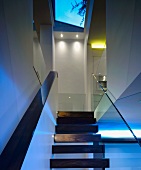 Wooden stairs in open stairwell with skylight in contemporary house