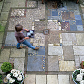 Patterned stone slabs in the outdoor area, planted pots and person with tray