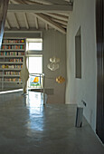 Puristically furnished living room with bookshelf, modern lamps and concrete floor