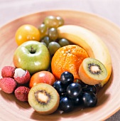 A bowl of grapes, apples and exotic fruits