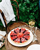 Berry cake and a glass of wine on a garden table