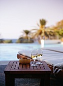 Two glasses of white wine on a side table by a pool