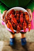 A woman holding a bowl of cooked crayfish