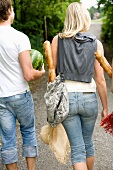 A man and a woman carrying baguettes and water melons