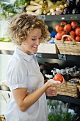 Frau kauft Tomaten im Supermarkt