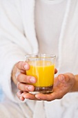 A person holding a glass of orange juice
