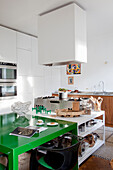 Moderne Küchenzeile mit grünem Esstisch und Edelstahlgeräten