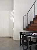 Grey table with chairs in front of staircase in open-plan room