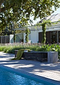 In front of contemporary house - sun lounger on wooden deck adjoining pool