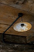 Vintage pendant lamp with rusty lampshade hanging from wooden ceiling